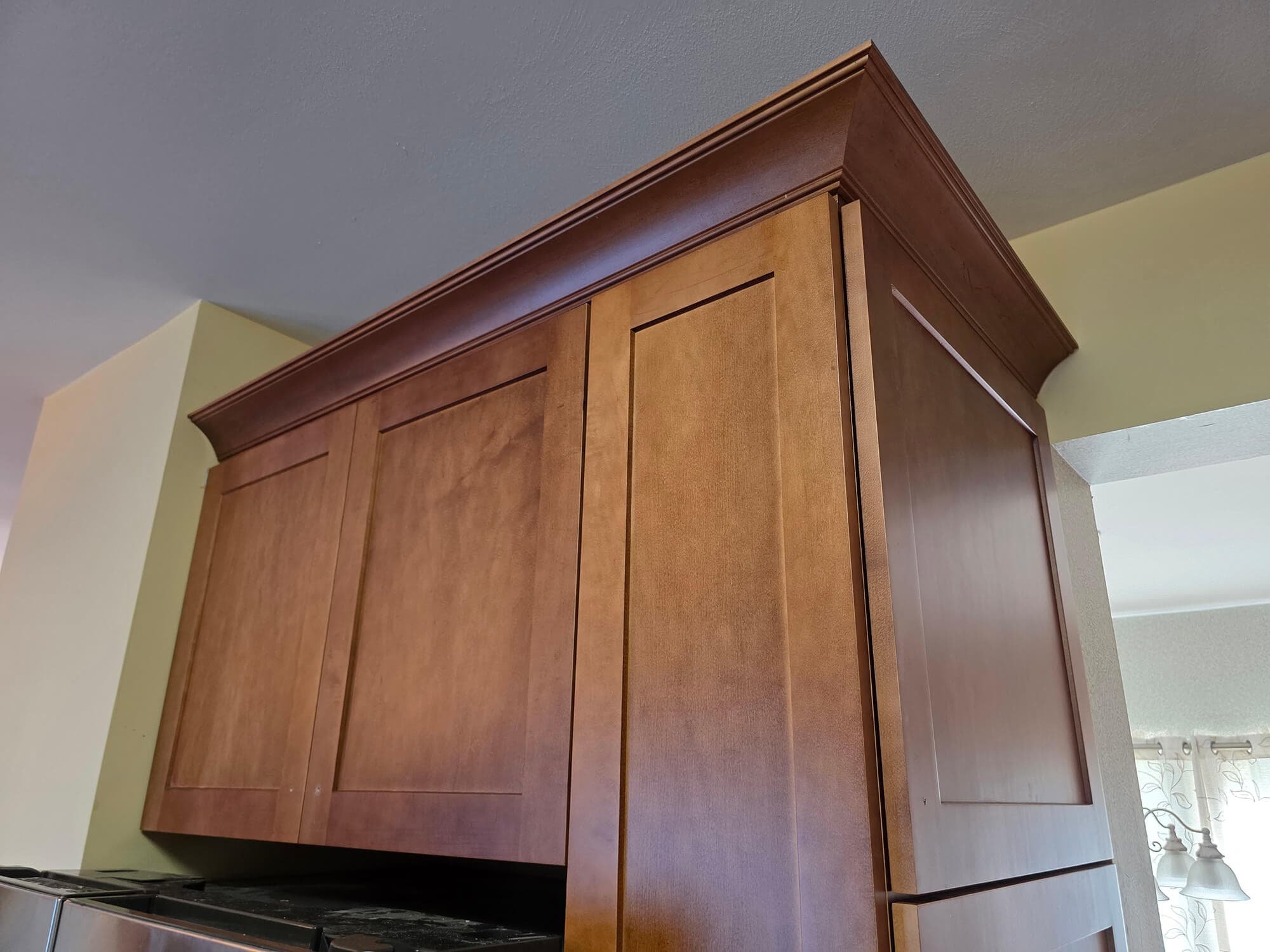 Finished cabinet refacing in a St. Louis kitchen: handcrafted solid-wood doors and crown molding by Professional Wood Interiors.